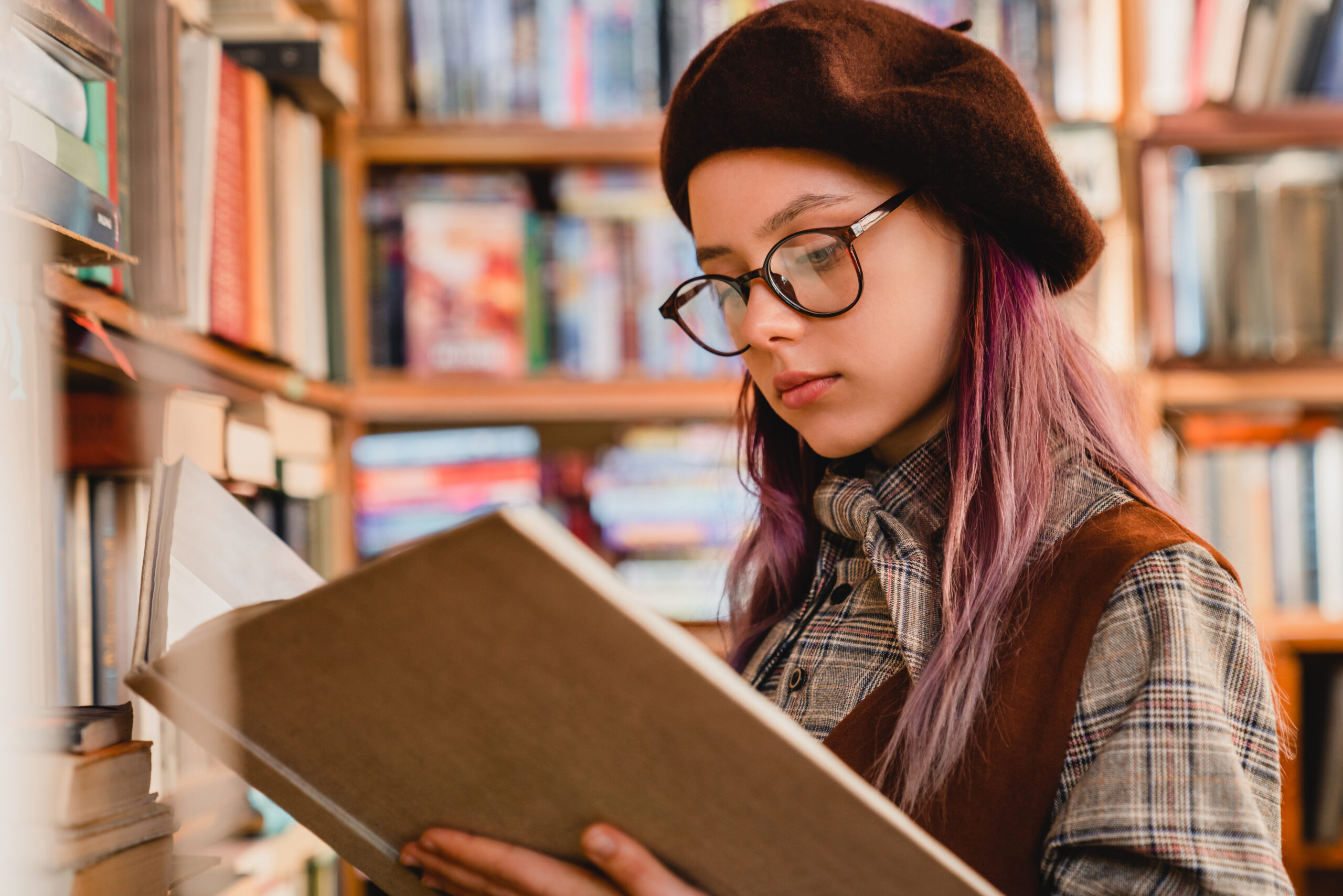 Intelligent young caucasian girl in glasses reading a book at the library Reading Habit: 6 Tips To Develop a Reading Habit